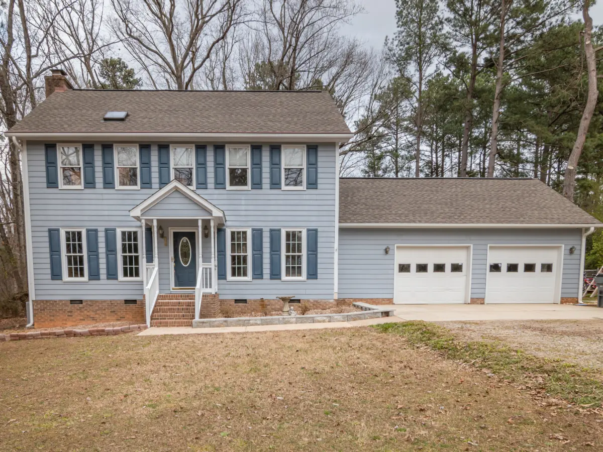A blue two story home with a two car garage and a new shingle roof.