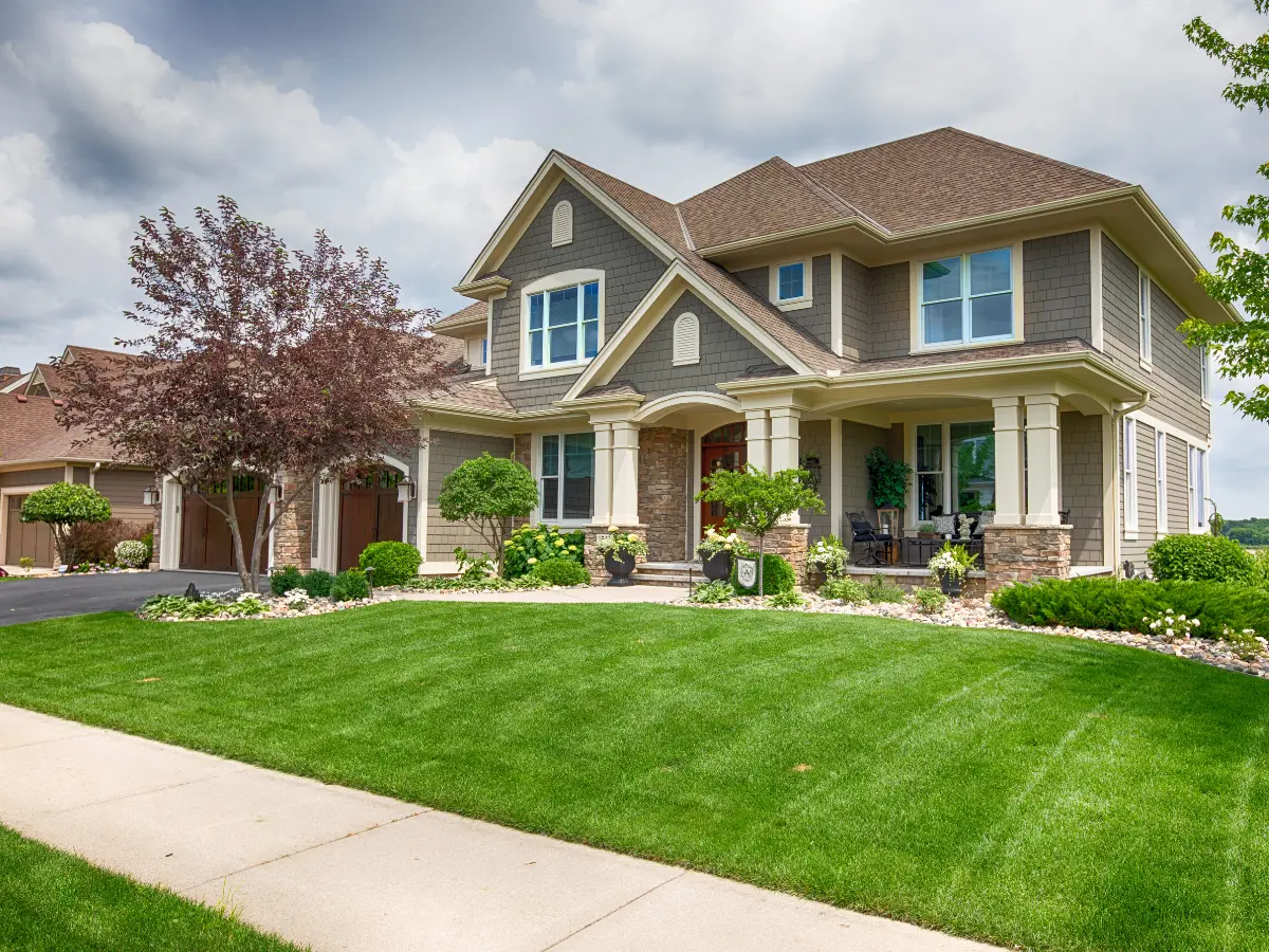 Large two story craftsman with stone accents and columns, finished in dark architectural shingles.