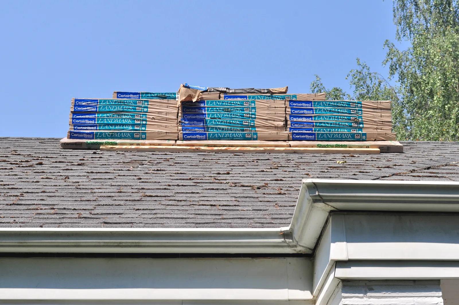 New shingle bundles stacked on an aging roof ready for replacement