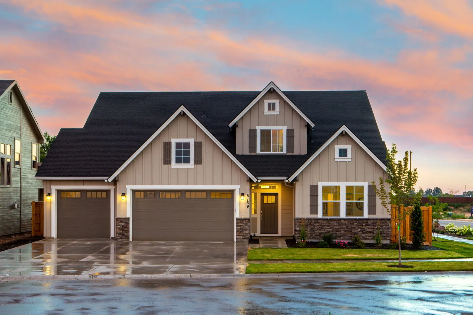 Two story home with a dark architectural shingle roof at sunset