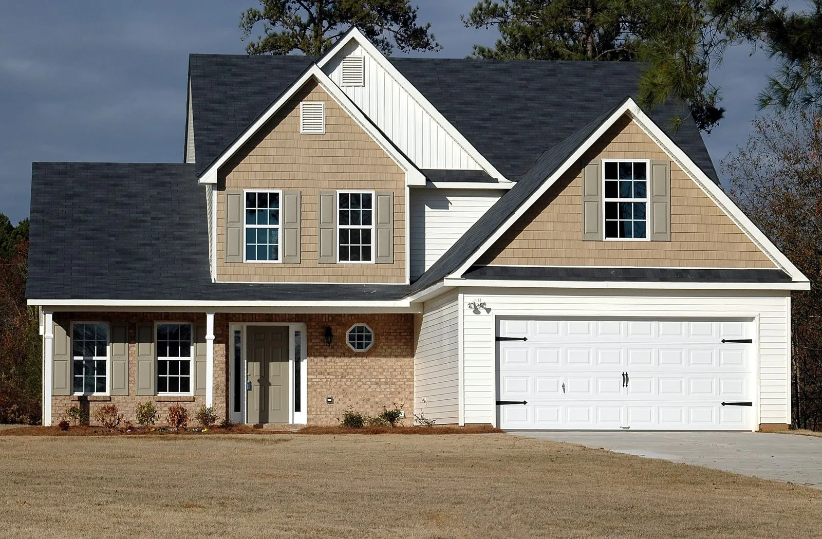 Two story home with a dark shingle roof under an overcast sky